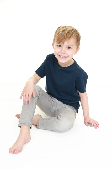 professional portrait photograph of boy sat on floor in casual pose on white background